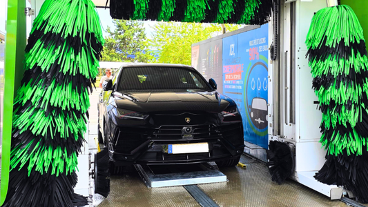 Voiture noire dans une station de lavage automatique illustrant l'importance de l'entretien matériel lavage auto pour un nettoyage optimal.